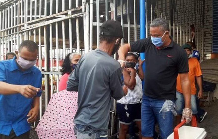 Voluntários servem água e comida de graça a pessoas na fila da Caixa